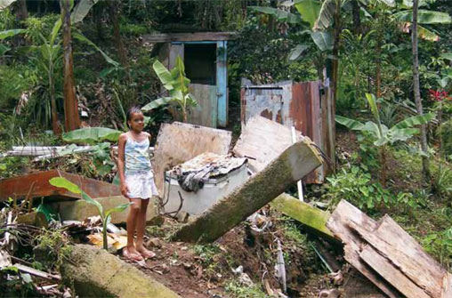 A young girl stands outside a home destroyed by a rainfall-triggered landslide in Castries, Saint Lucia.