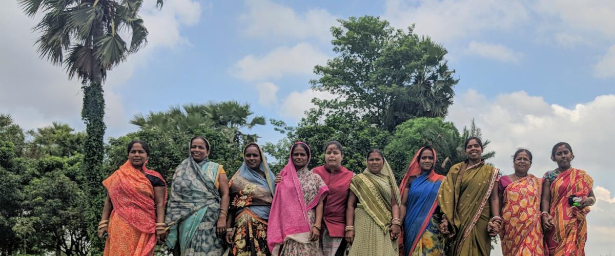 A group of women stand in a row in a field